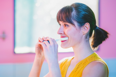 Eine Frau hat die Y-Brush zum Zähneputzen im Mund