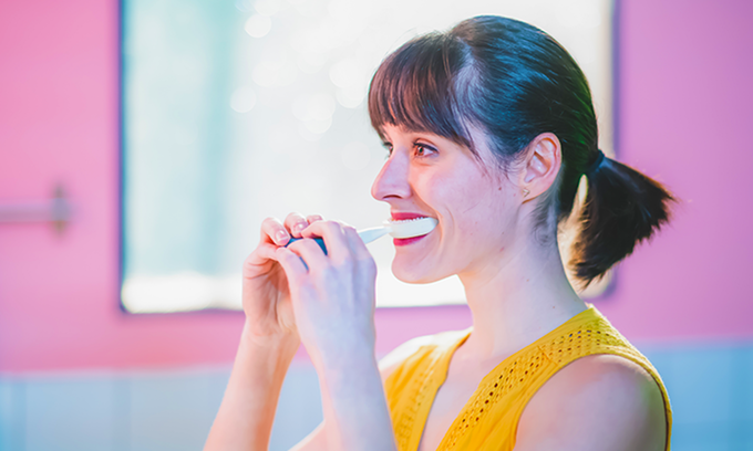 Eine Frau hat die Y-Brush zum Zähneputzen im Mund
