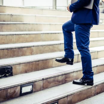 Close up of young businessman walking upstairs outside office.